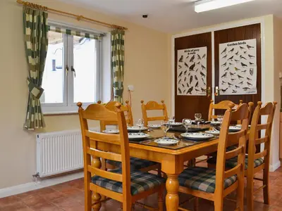 a dining room with a wooden table and chairs at Swallow Cottage in Llanfair Caereinion