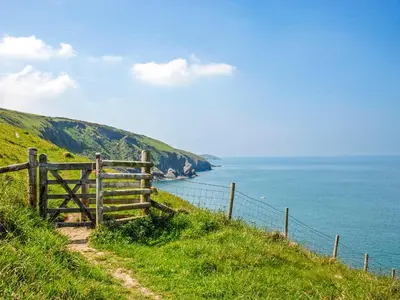 a fence on a hill next to the ocean at Seascape in New Quay