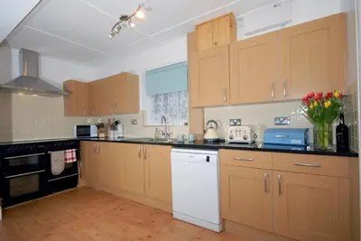 a kitchen with wooden cabinets and a white appliance at Seascape in New Quay