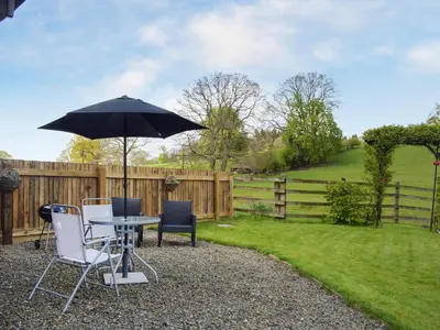 a table and chairs with an umbrella in a yard at The Granary in Kingsland