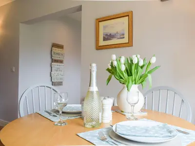 a dining room table with white plates and a vase of flowers at Little Bank Cottage in Lane to Richards Castle