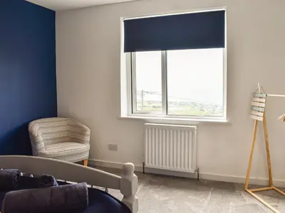 a living room with a window and a chair at Bryn Derwen in Harlech