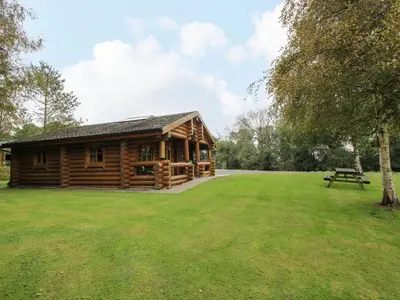 a log cabin with a picnic table in a field at Brynallt Country Park in Ellesmere