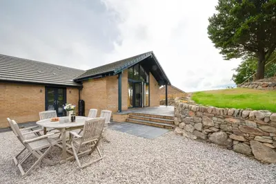 a patio with a table and chairs and a stone wall at 3 Bed in Barmouth oc-wah701 in Barmouth