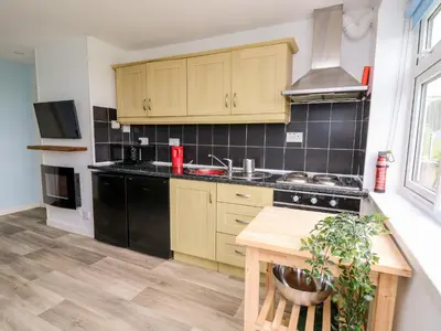 a kitchen with wooden cabinets and a stove top oven at Cwtsh Cragen in New Quay