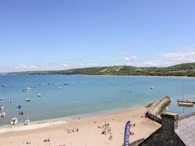 a beach with a bunch of boats in the water at Cwtsh Cragen in New Quay