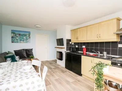 a kitchen and a dining room with a table in a room at Cwtsh Cragen in New Quay