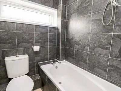 a bathroom with a toilet and a tub and a sink at Cwtsh Cragen in New Quay