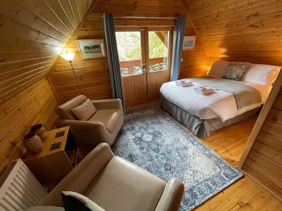 a bedroom with a bed and a couch in a room at Luxury 3 bedroom, 3 bathroom lodge with hot tub in Llanbedr