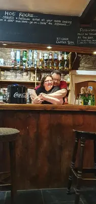 a man and a woman standing behind a bar at Dinas Castle Inn (The Dragons Back) in Brecon