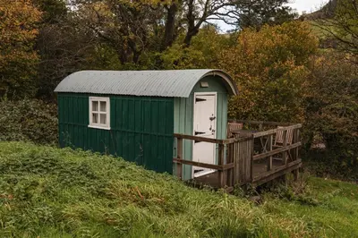 a green shed with a white door on a hill at Dinas Castle Inn (The Dragons Back) in Brecon
