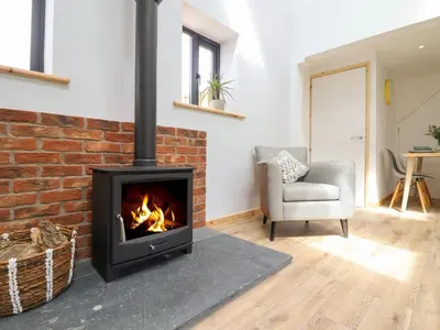 a living room with a brick fireplace and a chair at Little Nook in Corwen