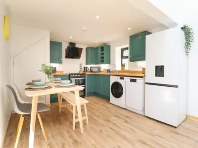 a kitchen with green cabinets and a table at Little Nook in Corwen