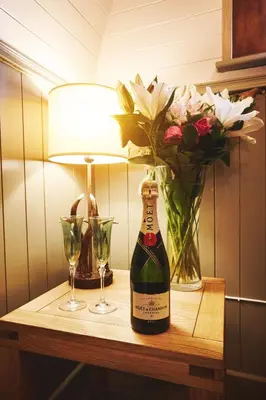 a table with a bottle of wine and a vase of flowers at Romantic Croft with Private Hot Tub in Shrewsbury