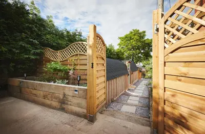 a wooden fence with a wooden gate with a garden at Romantic Croft with Private Hot Tub in Shrewsbury