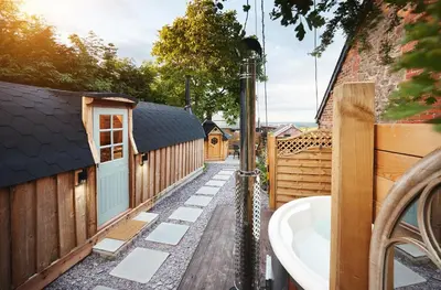 a bathroom with a bath tub next to a fence at Romantic Croft with Private Hot Tub in Shrewsbury