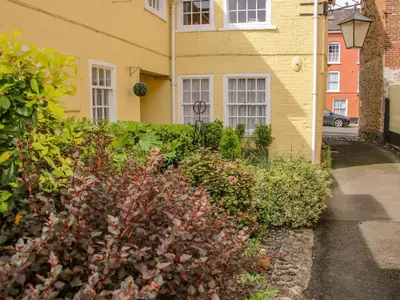 a yellow house with a hedge in front of it at 138C Old Star and Garter Mews in Ludlow