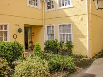 a yellow house with plants in front of it at 138C Old Star and Garter Mews in Ludlow