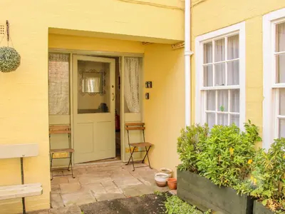 a yellow house with a door and chairs on a patio at 138C Old Star and Garter Mews in Ludlow