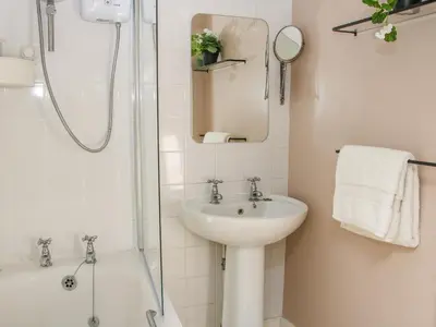 a white bathroom with a sink and a shower at 138C Old Star and Garter Mews in Ludlow
