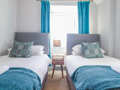 two beds in a room with blue curtains at Ty Cerrig in Dyffryn
