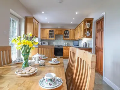 a kitchen with a wooden table with a vase of flowers at Ty Cerrig in Dyffryn