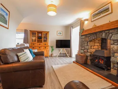 a living room with a couch and a stone fireplace at Ty Cerrig in Dyffryn