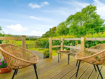 two chairs and a table on a wooden deck at Cwtch Enrico - Uk39064 in Scyborycoed