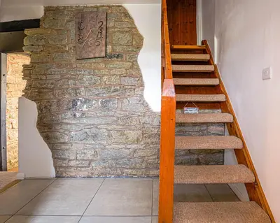 a staircase in a room with a stone wall at Cosy cottage in rural Culmington, Ludlow in Culmington