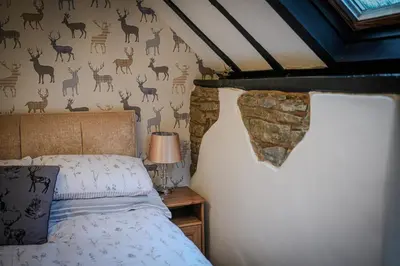 a bedroom with a bed with deer on the wall at Cosy cottage in rural Culmington, Ludlow in Culmington