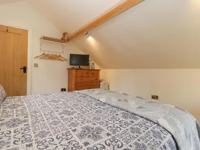 a bedroom with a bed and a tv on the wall at The Cart Barn in Leominster