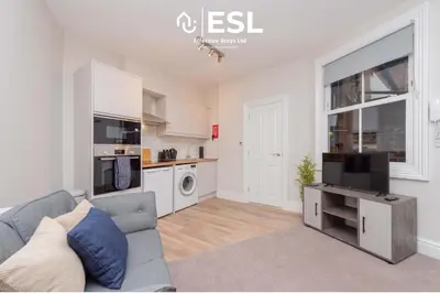 a living room with a couch and a tv and a kitchen at Studio 1, First Floor Town Centre Apartment in Shrewsbury