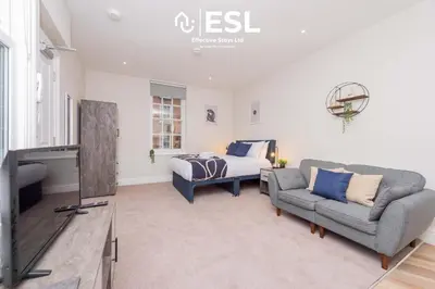 a bedroom with a bed and a couch and a tv at Studio 1, First Floor Town Centre Apartment in Shrewsbury