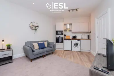 a living room with a couch and a kitchen at Studio 1, First Floor Town Centre Apartment in Shrewsbury