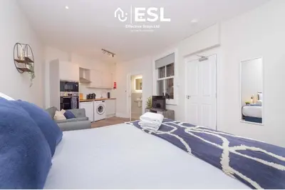 a bedroom with a large bed and a living room at Studio 1, First Floor Town Centre Apartment in Shrewsbury