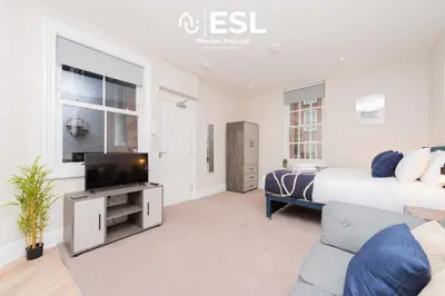 a bedroom with a bed and a tv and a couch at Studio 1, First Floor Town Centre Apartment in Shrewsbury