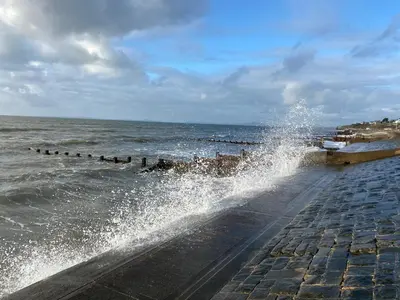 a large splash of water on a sidewalk next to the ocean at Stunning Pet-Friendly Home with Hot Tub less than one minute walk from Barmouth Beach in Barmouth
