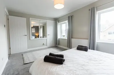 a bedroom with a large white bed with two chairs at Stunning Pet-Friendly Home with Hot Tub less than one minute walk from Barmouth Beach in Barmouth