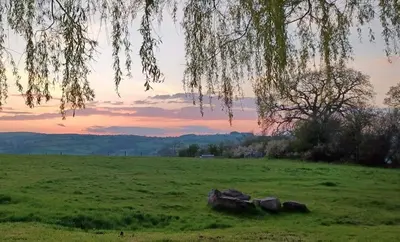 a field with rocks in the grass with a sunset at 1 Bed Lodge-Sleeps 4-Pet Friendly-Free Parking in Hereford
