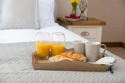 a tray of orange juice and croissants on a bed at Snowdonia Holiday Cottage in Bala