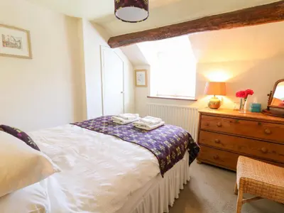 a bedroom with a bed and a dresser and a window at Chancery Cottage in Hay-on-Wye