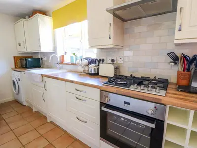 a kitchen with white cabinets and a stove top oven at Chancery Cottage in Hay-on-Wye