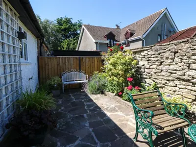 a garden with a bench and a stone fence at Chancery Cottage in Hay-on-Wye