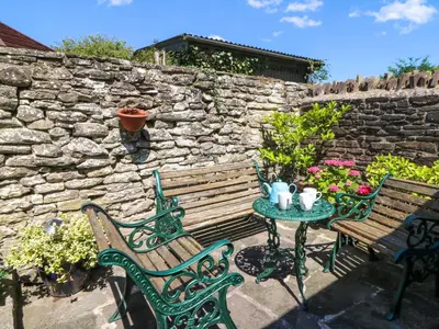 two benches and a table with a stone wall at Chancery Cottage in Hay-on-Wye