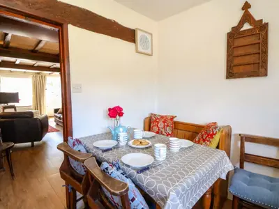 a dining room with a table with plates and flowers on it at Chancery Cottage in Hay-on-Wye