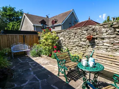 a patio with a bench and a table and a stone wall at Chancery Cottage in Hay-on-Wye