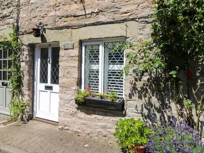 a stone cottage with a white door and a window at Chancery Cottage in Hay-on-Wye
