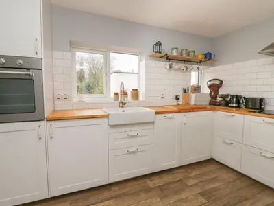 a kitchen with white cabinets and a sink at Cysgod Y Coed in Machynlleth