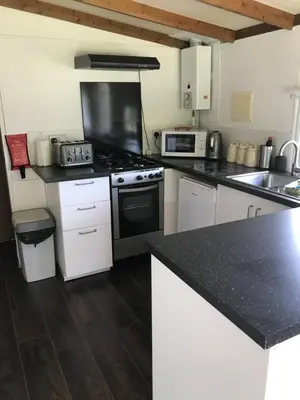 a kitchen with white cabinets and a black counter top at Pheasant Lodge in Builth Wells