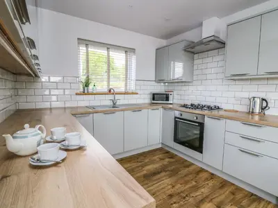 a kitchen with white cabinets and a wooden table at Llyn Cae Ty Nant Fishery Holiday Let in Lampeter